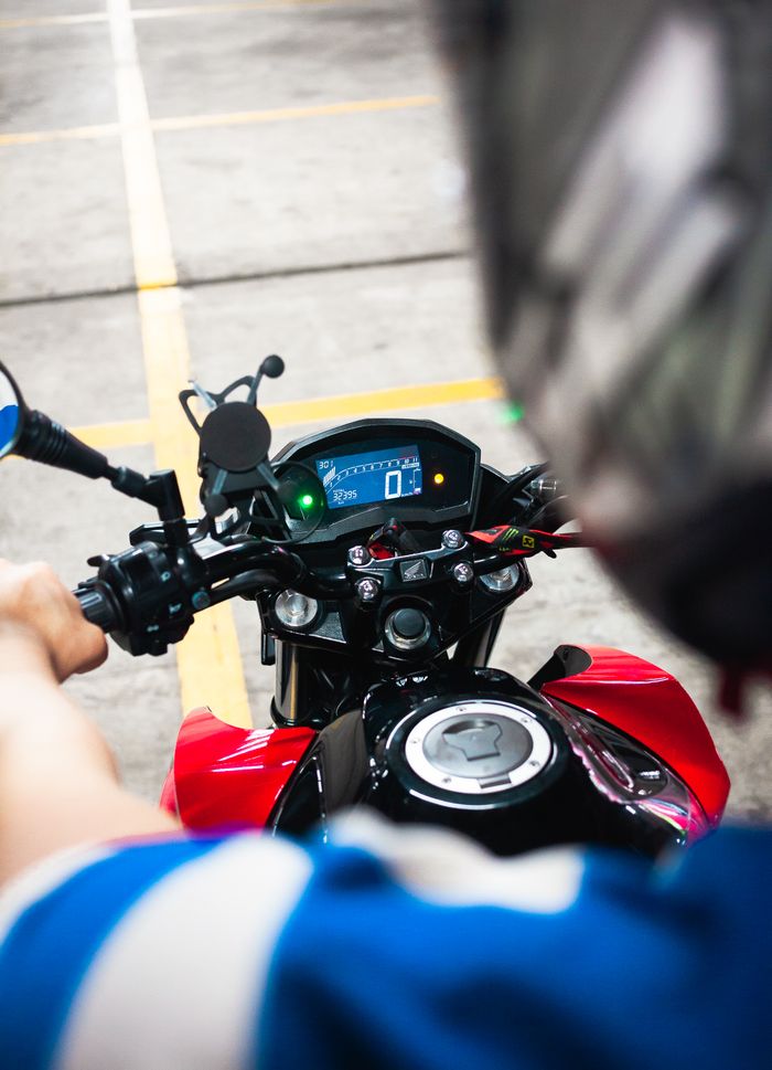 Dynamic view from rider's perspective on motorcycle showing digital speedometer and hands on handlebars.